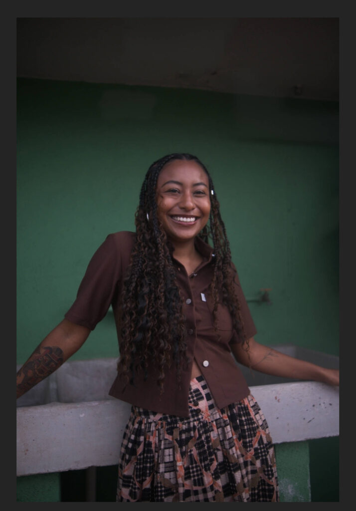 Portrait of the woman against the green wall with the background concrete structure removed using ON1 Photo RAW's object removal tool, showing a visible brush stroke outline